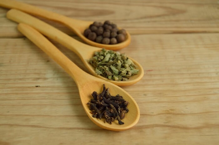 clove and thyme on brown wooden spoons